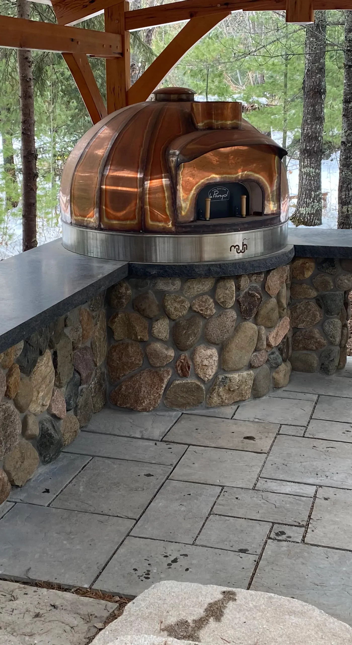 A wood fired pizza oven in an outdoor kitchen with intricate rock work done by Rock Country Masonry.